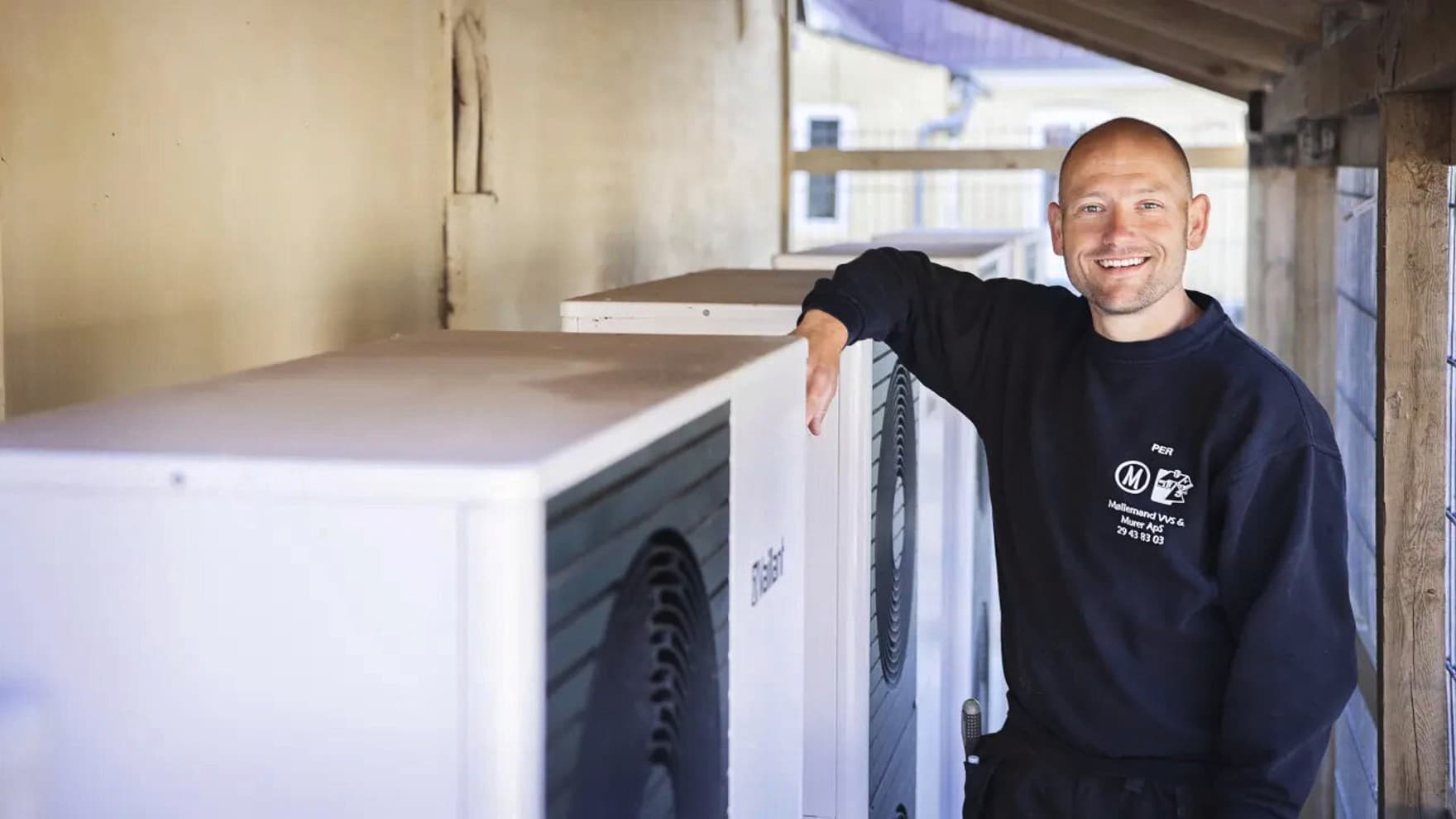 Installatøren læner sig op ad en varmepumpe