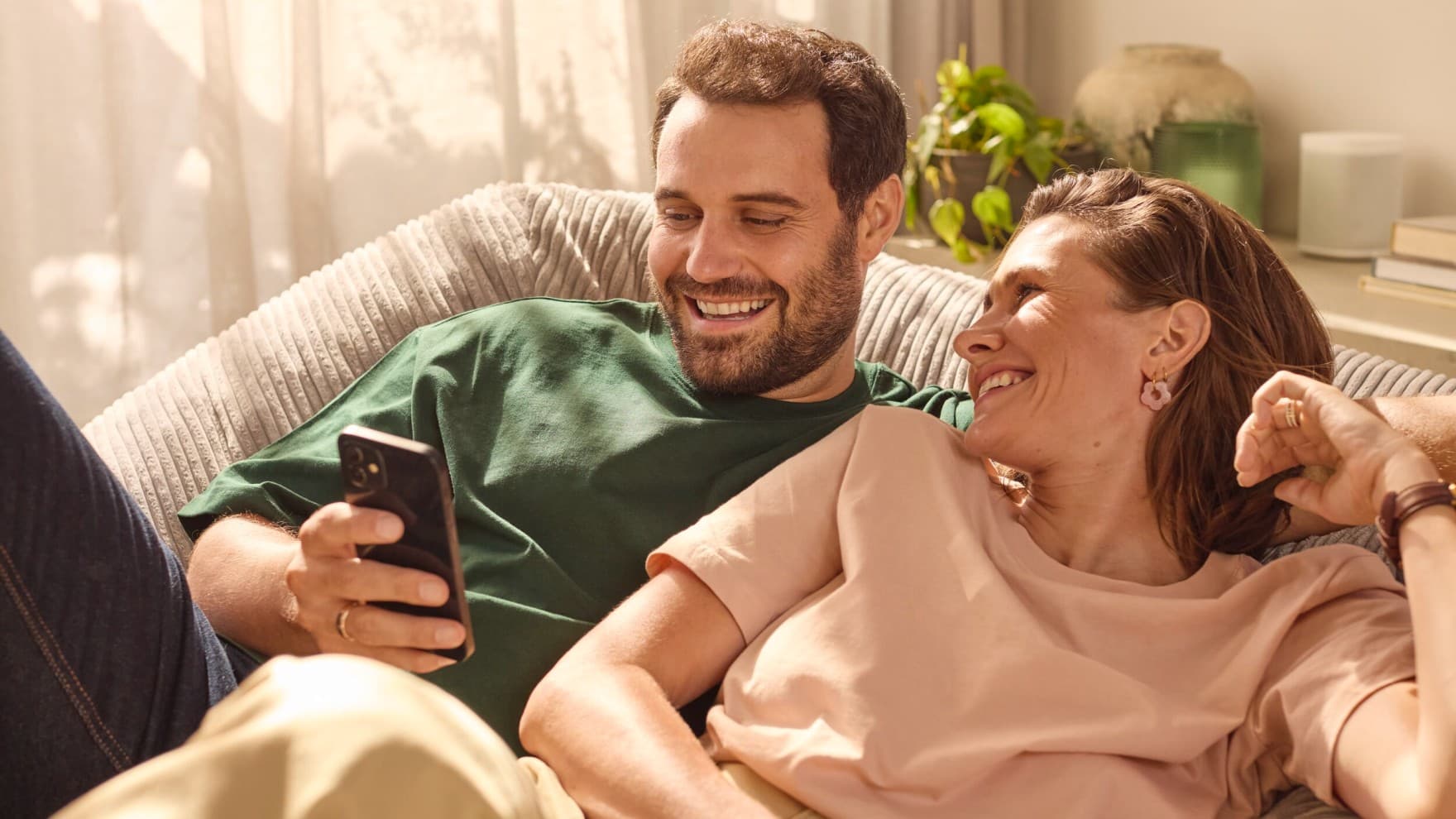 Par sidder på sofaen og kigger på en telefon