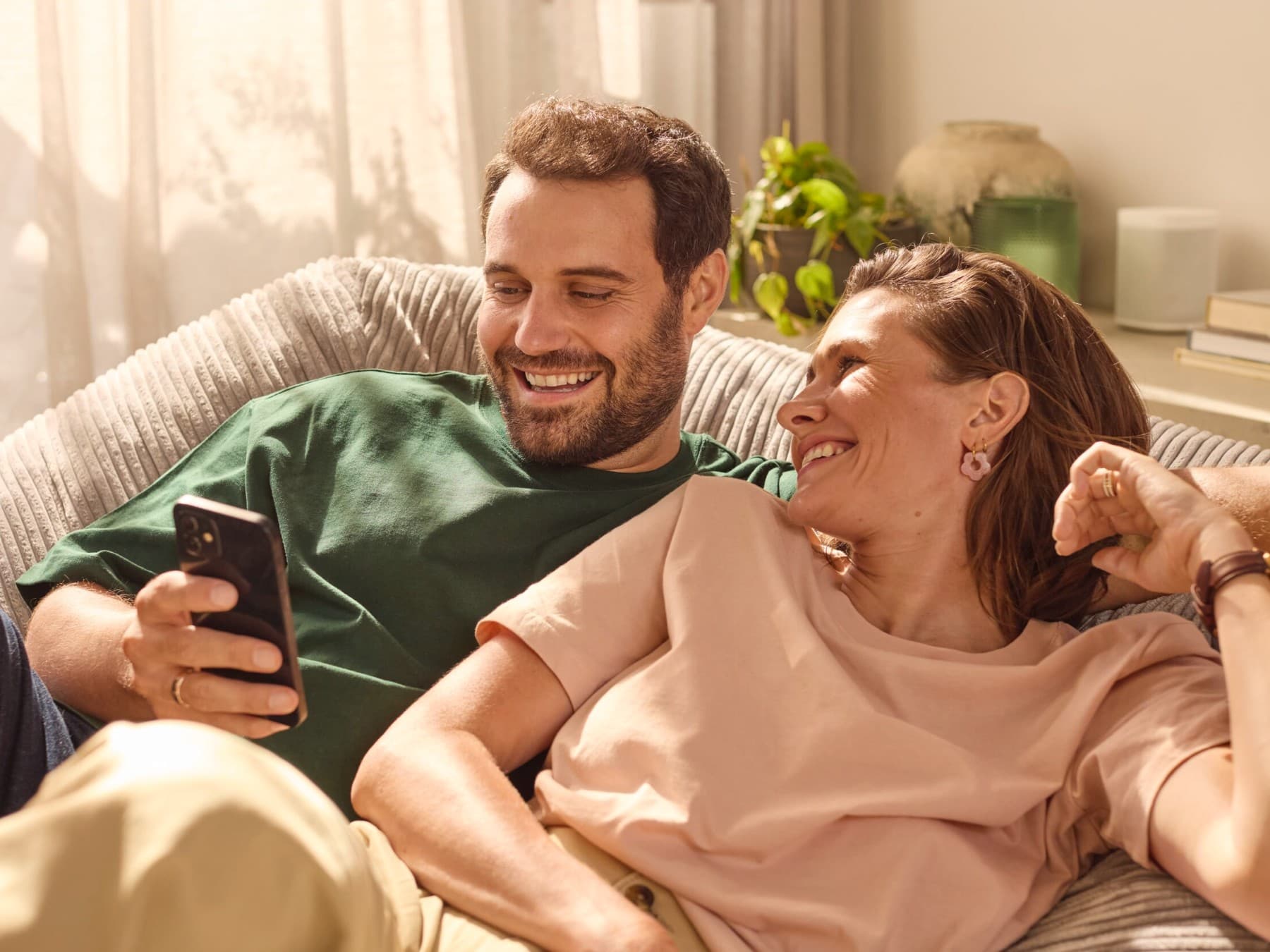 Par sidder på sofaen og tjekker energiforbruget på en app