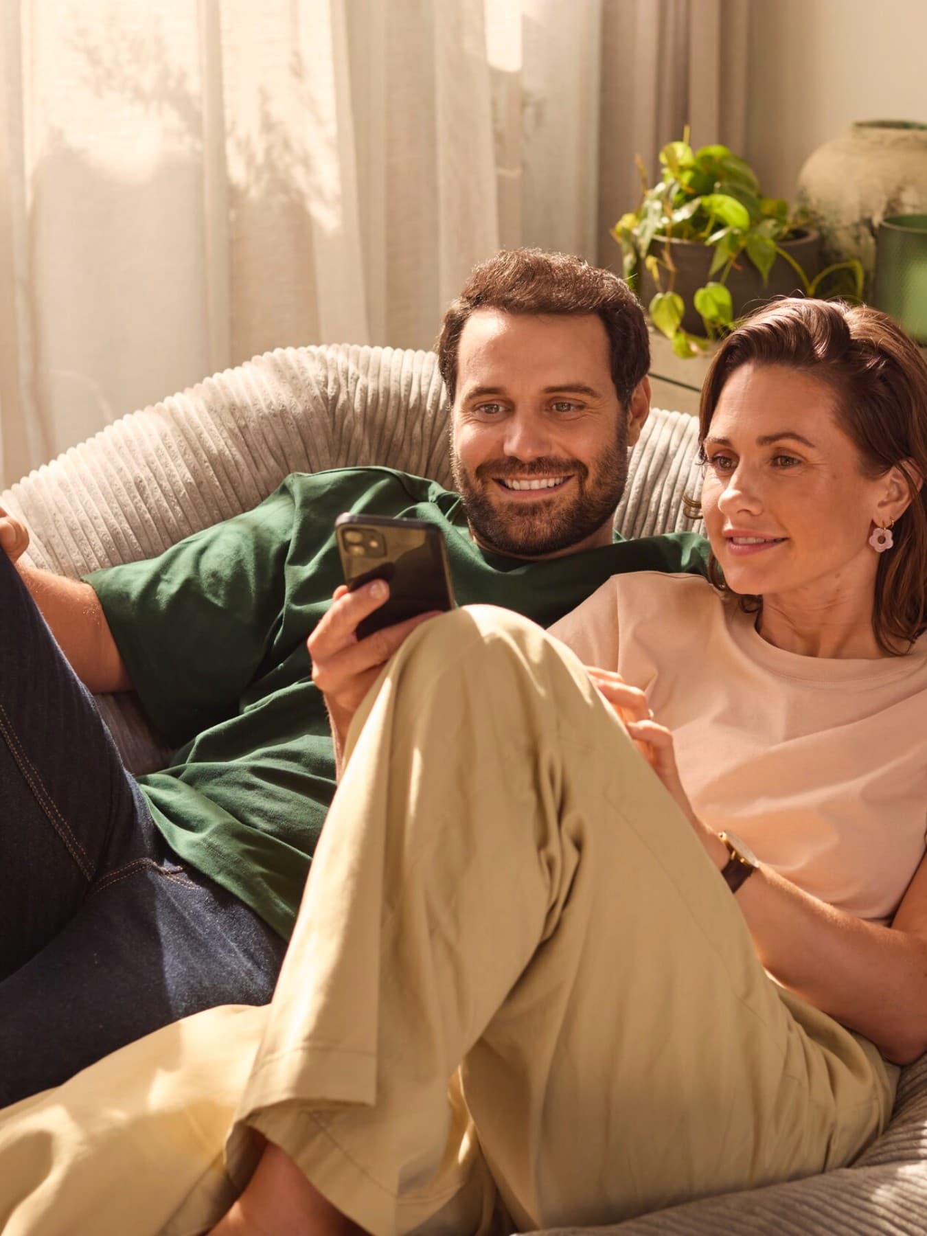 Par sidder på en sofa og kigger på en smartphone