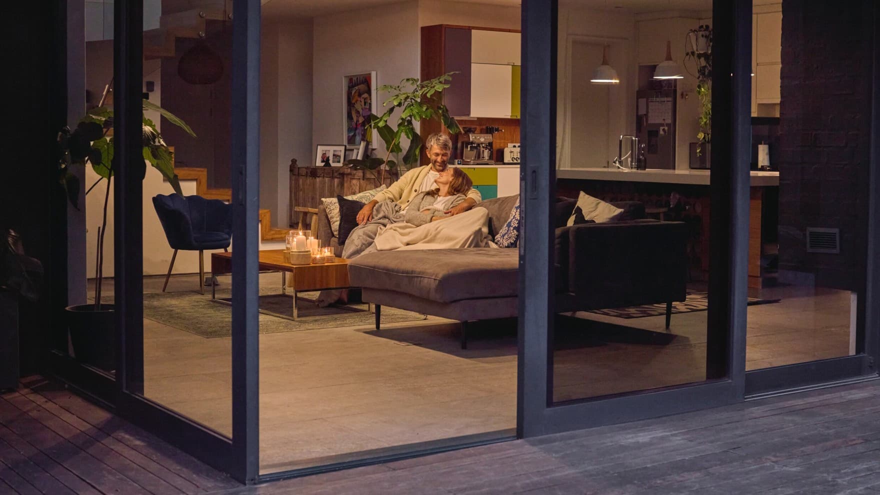Par siddende på sofaen med terrassedøren åben