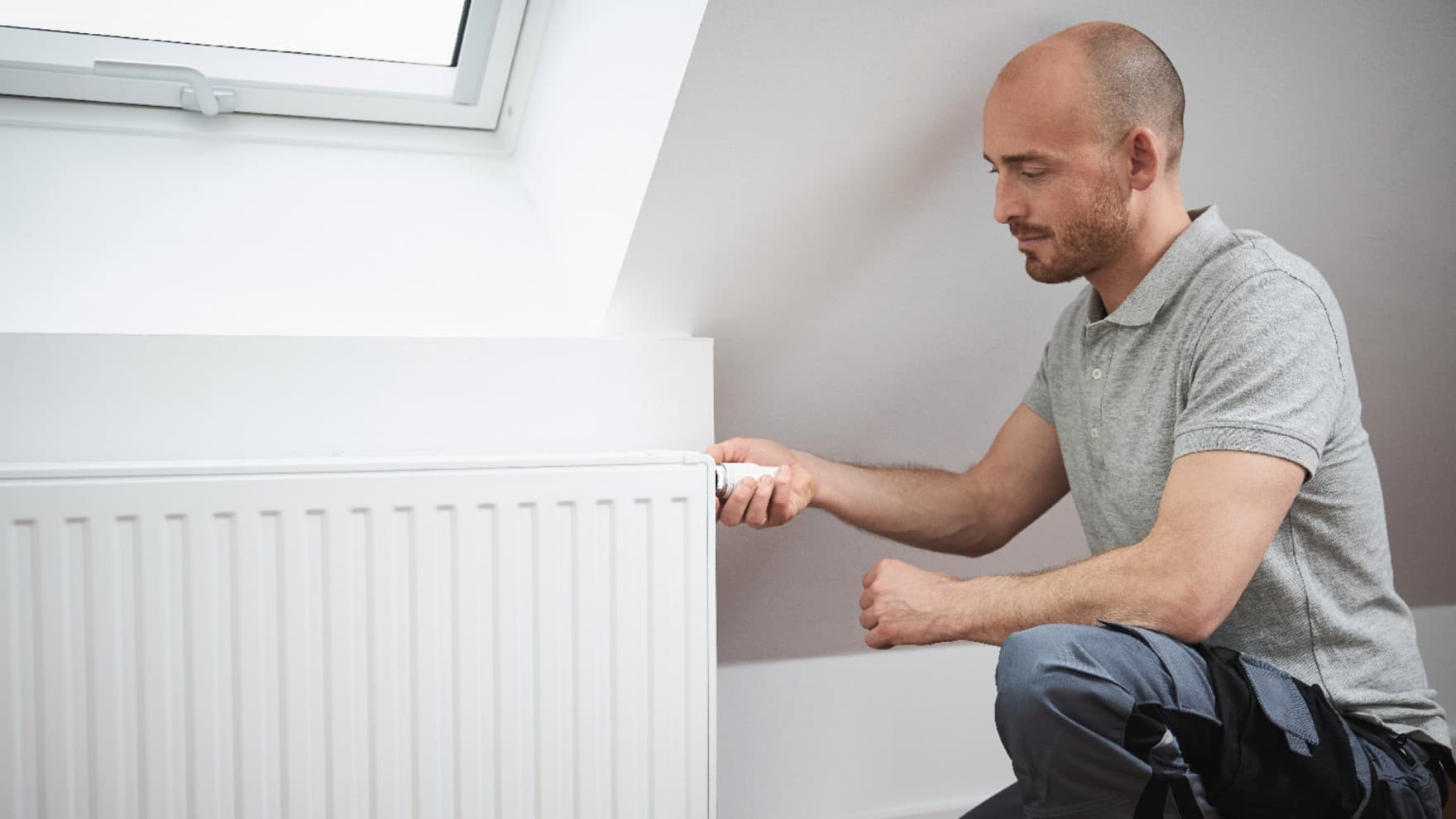 Mand, der tænder termostaten på en radiator