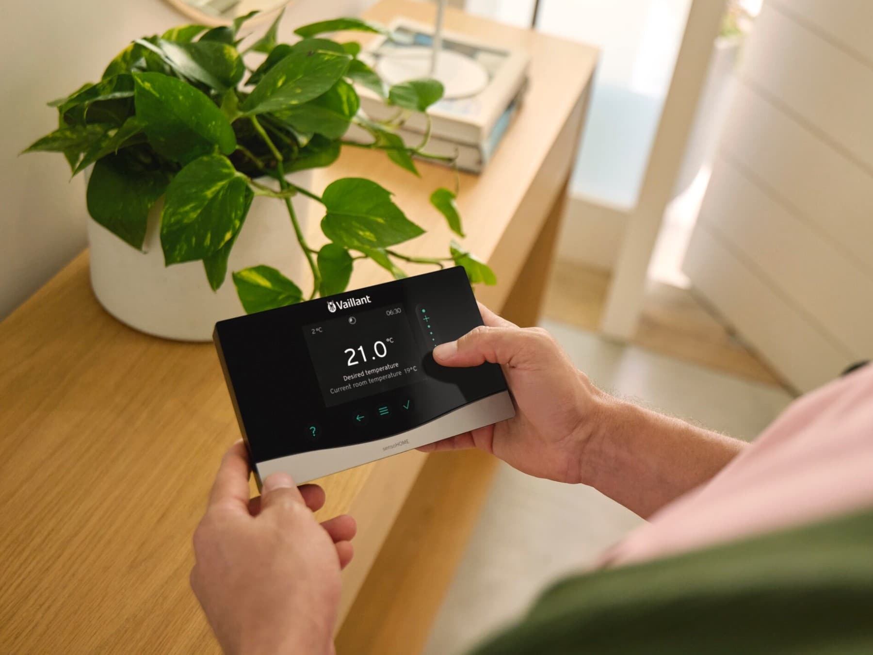 Mand med systemkontrollen sensoCOMFORT i hånden