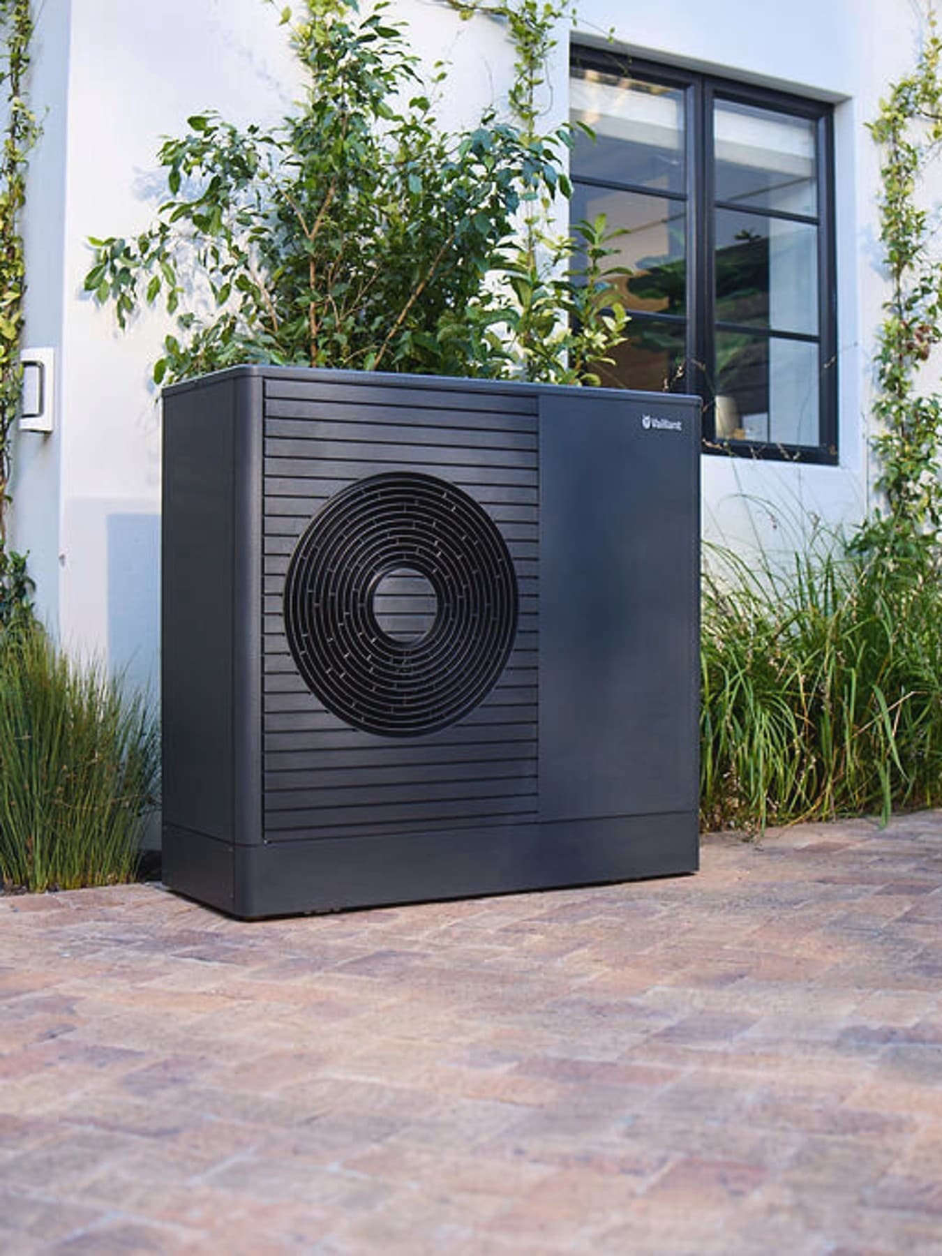 Mørk Vaillant aroTHERM plus varmepumpe i forhaven til et hus