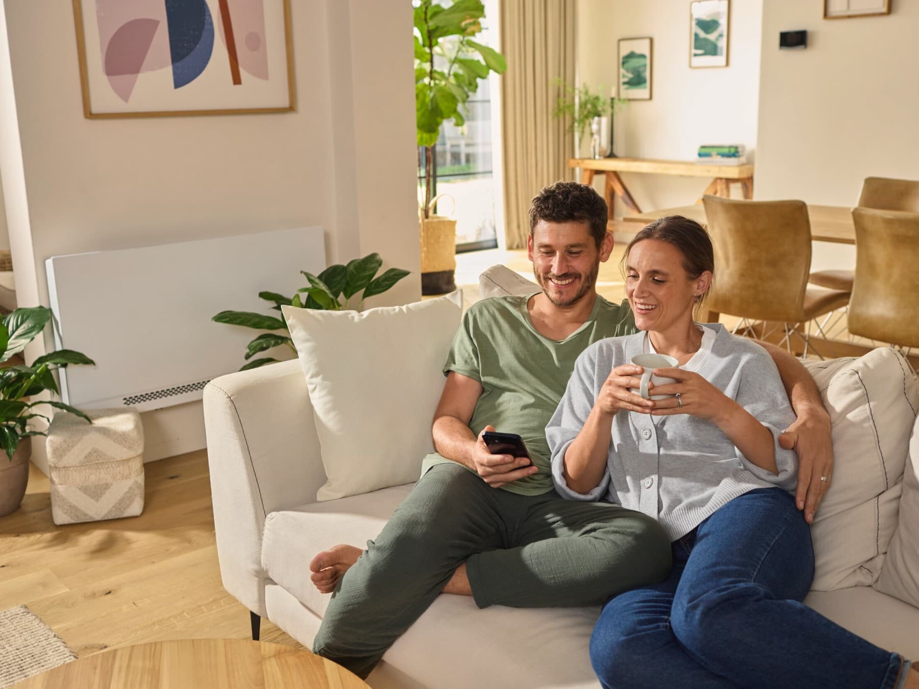 Par sidder på sofaen og kigger på en smartphone