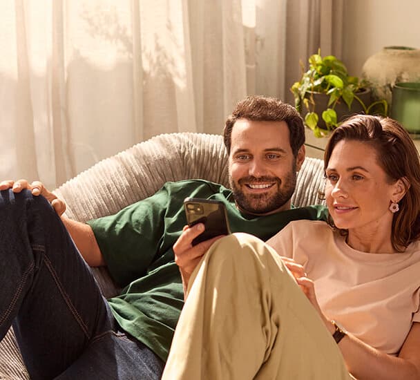 Et par, der sidder i sofaen og kigger på en smartphone