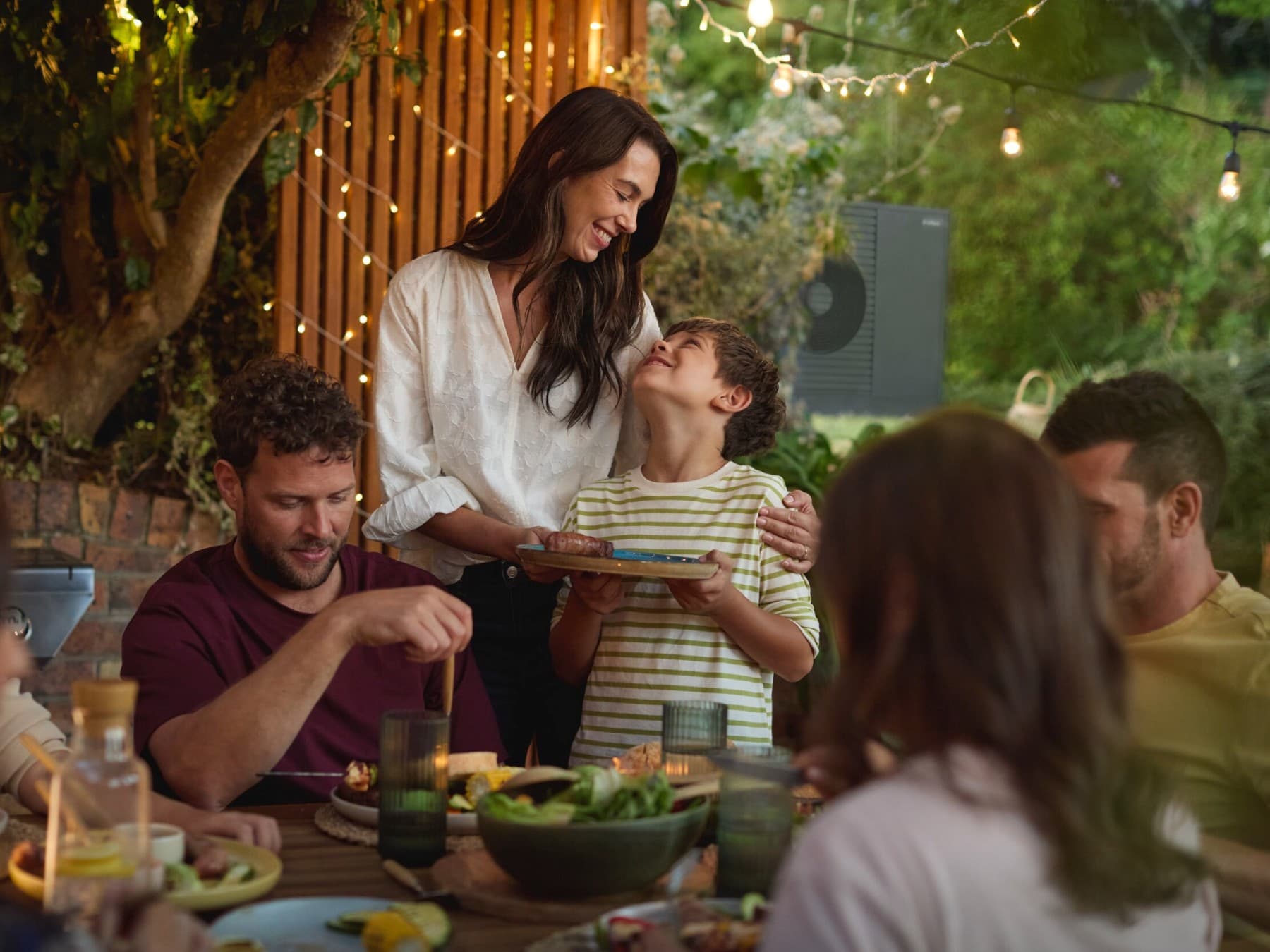 Familie nyder en grillfest i haven med venner