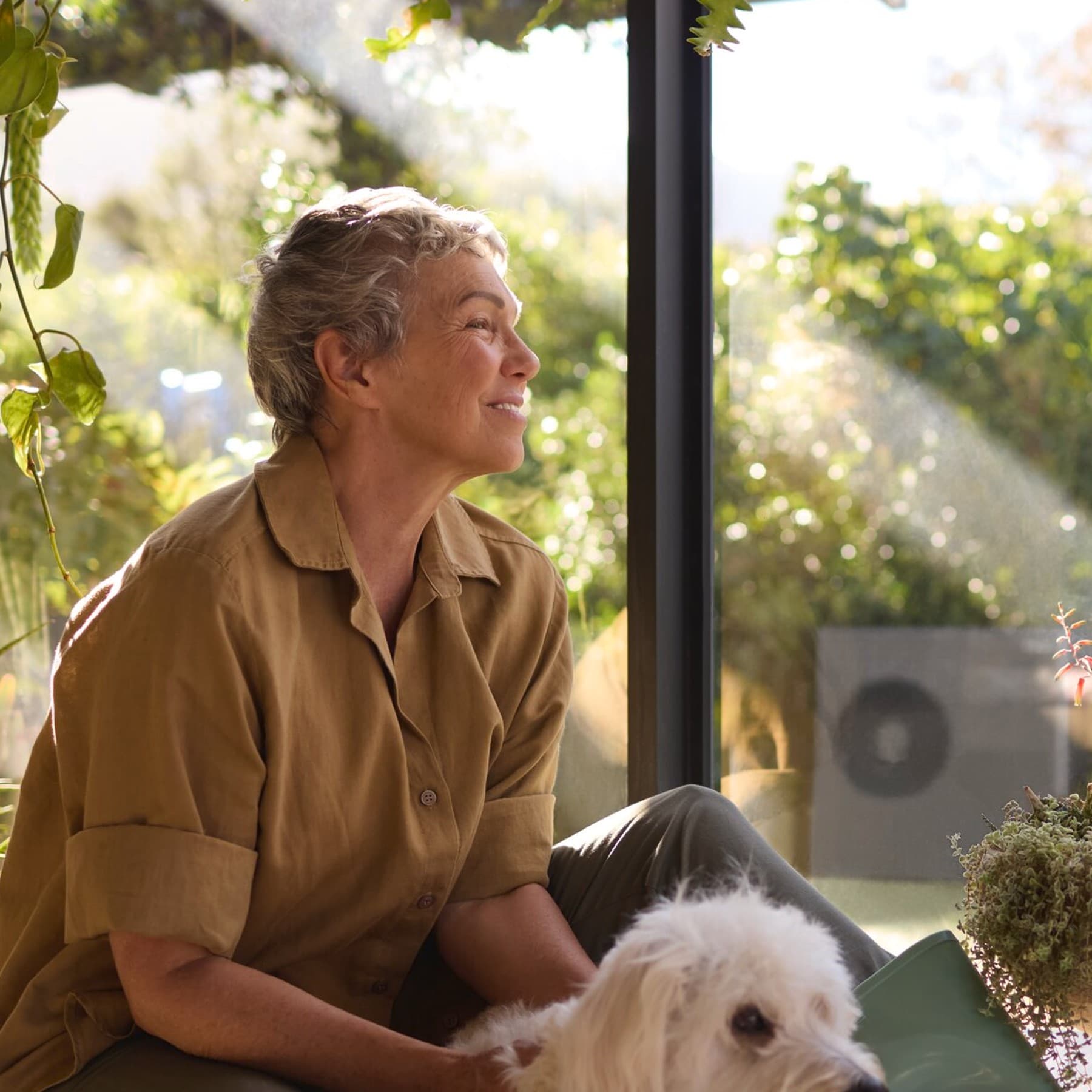 En kvinde, der sidder ved vinduet sammen med sin hund