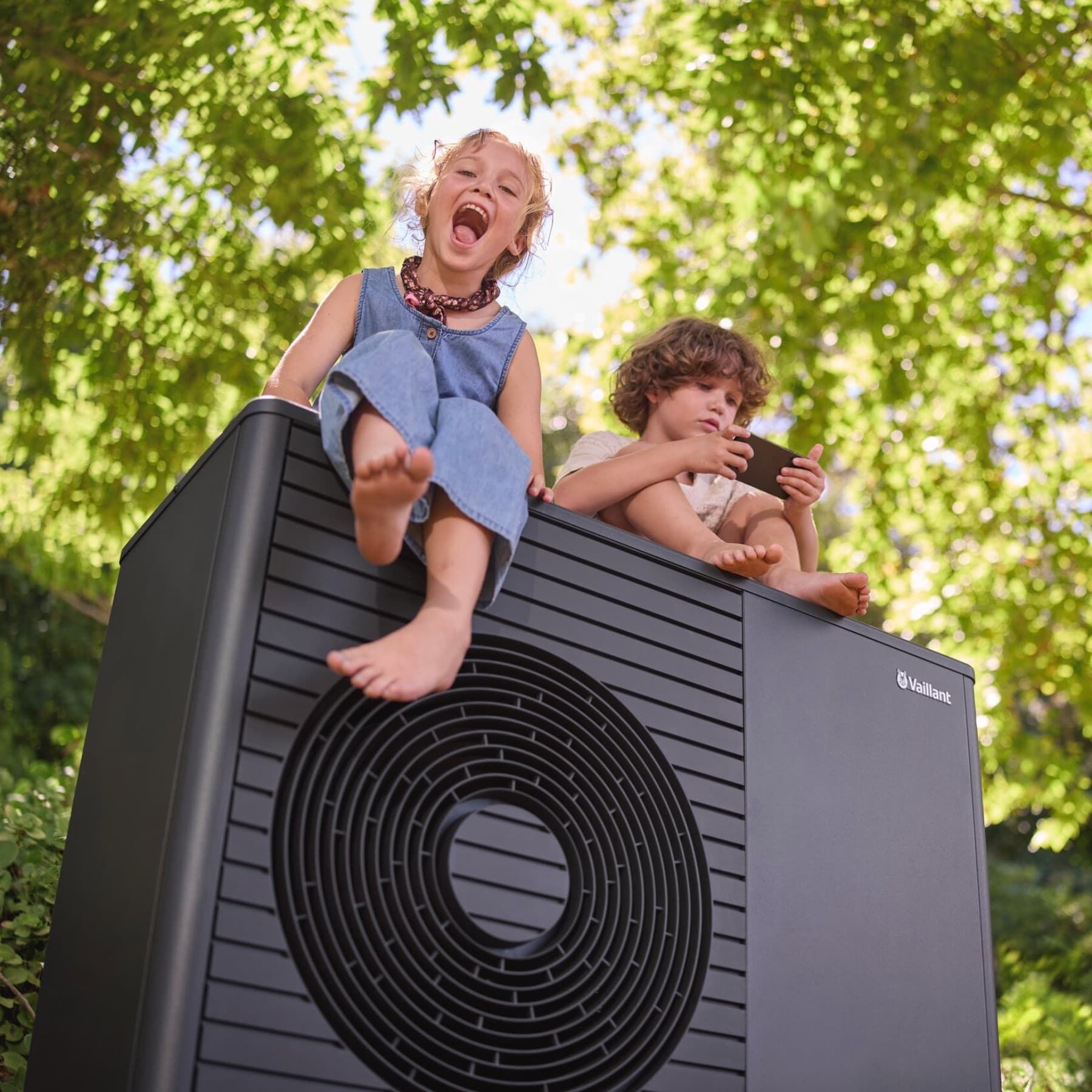 To børn sidder på en Vaillant aroTHERM plus varmepumpe