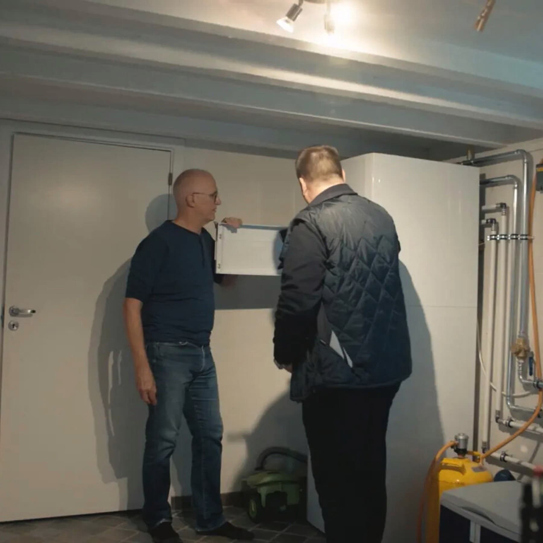 Iversen og en tekniker kigger på en varmepumpe