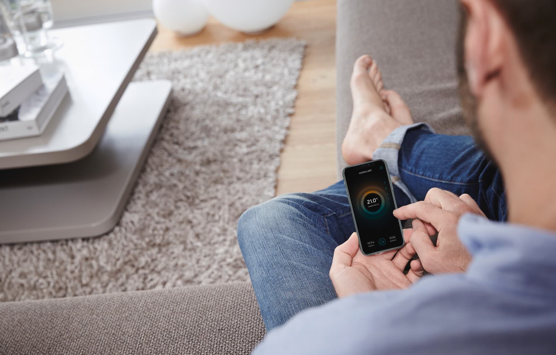 Person sidder med mobil telefon, hvor myVaillant appen er åben